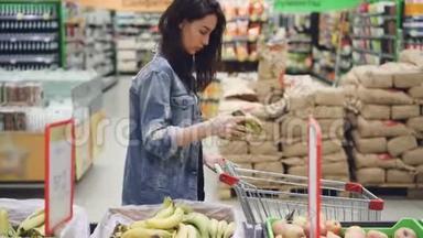 可爱的女孩快乐的顾客在超市里挑选水果，买香蕉、苹果和橘子，然后把它们放进超市